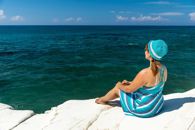 Una chica joven y bonita descansa a orillas del mar azul.