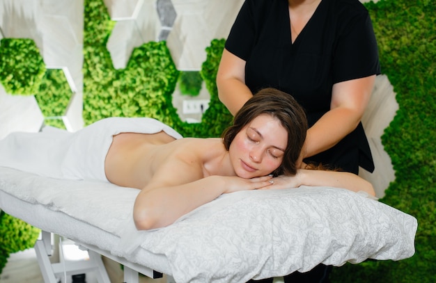 Una chica joven y bonita está disfrutando de un masaje cosmetológico profesional en el Spa. Cuidado del cuerpo. Salón de belleza.