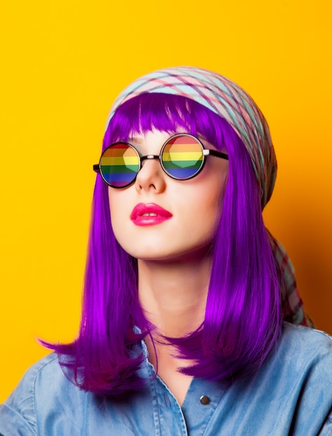 Chica joven con cabello morado y arco iris en suglasses en amarillo