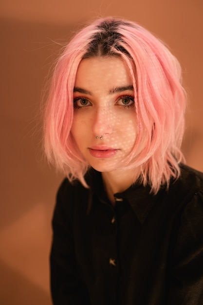 Chica joven con cabello rosado en retrato de estudio de fondo de pared naranja