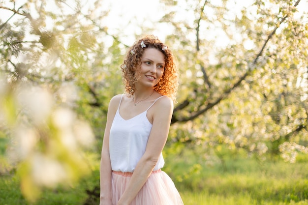 La chica joven camina en el parque verde de la primavera que disfruta de la naturaleza floreciente. Muchacha sonriente sana que hace girar en el césped de la primavera. Alergia sin