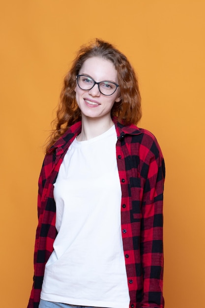 Foto chica joven en una camisa a cuadros con gafas sobre un fondo naranja