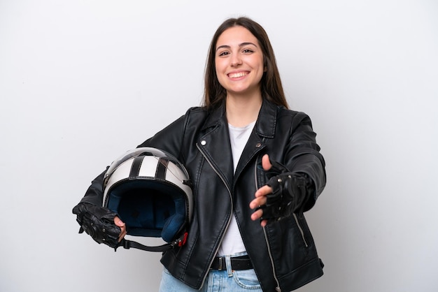 Chica joven con un casco de motocicleta aislado sobre fondo blanco estrechando la mano para cerrar un buen trato