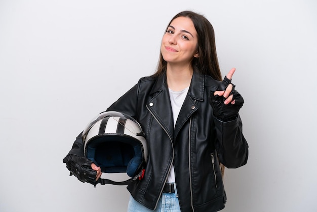 Chica joven con un casco de motocicleta aislado sobre fondo blanco mostrando y levantando un dedo en señal de lo mejor