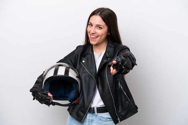 Chica joven con un casco de motocicleta aislado sobre fondo blanco sorprendido y apuntando al frente