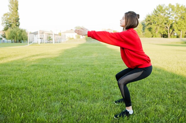 Chica joven en una chaqueta deportiva roja entra en deportes en el estadio