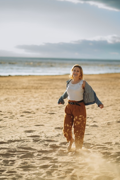 Chica joven en chaqueta de mezclilla disfrutar del sol en la playa en las noches de verano