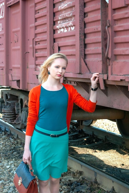 Una chica joven con una chaqueta roja en el ferrocarril.