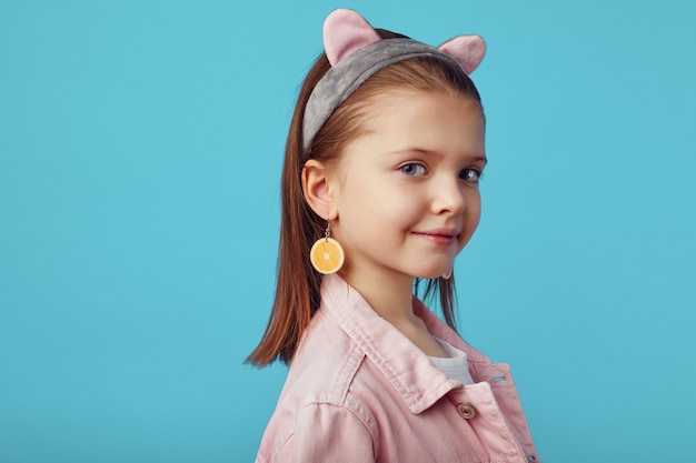 Foto chica joven en chaqueta rosa posando adorable contra el fondo azul del estudio