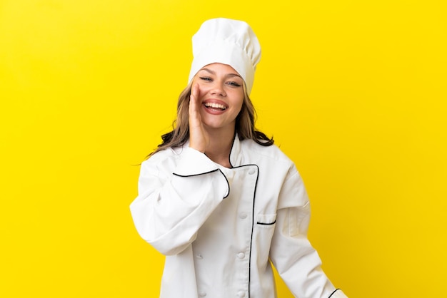 Chica joven chef ruso aislada sobre fondo amarillo gritando con la boca abierta