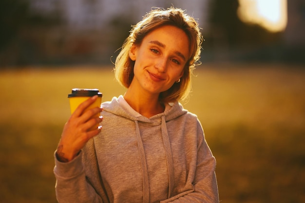 chica joven con una chica de café bebe lat de un vaso de papel en el procesamiento de fotos vintage de la calle