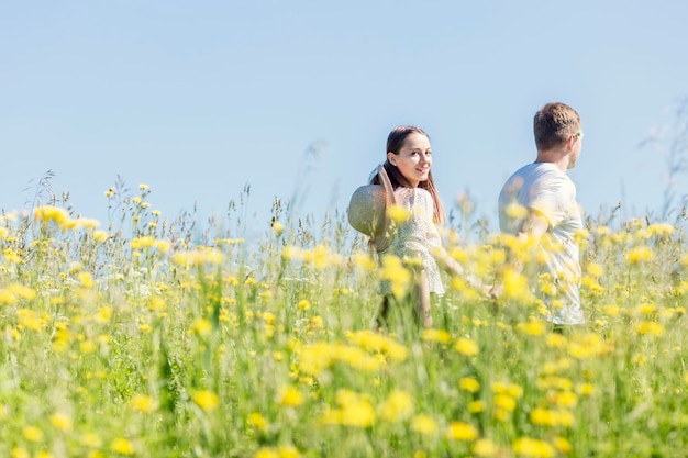 Chica joven con un chico en un campo en un día soleado Novio sosteniendo la mano de su novia Grandes vacaciones de verano en la naturaleza