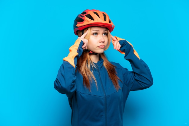 Chica joven ciclista aislada sobre fondo azul teniendo dudas y pensando