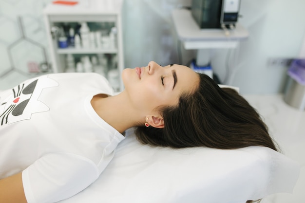 Chica joven en la clínica de spa de belleza cosmética esperando procedimiento de belleza