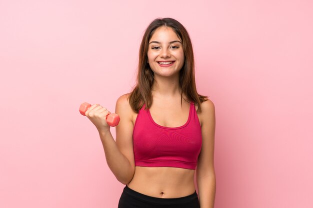 Chica joven deporte sobre rosa aislado haciendo pesas