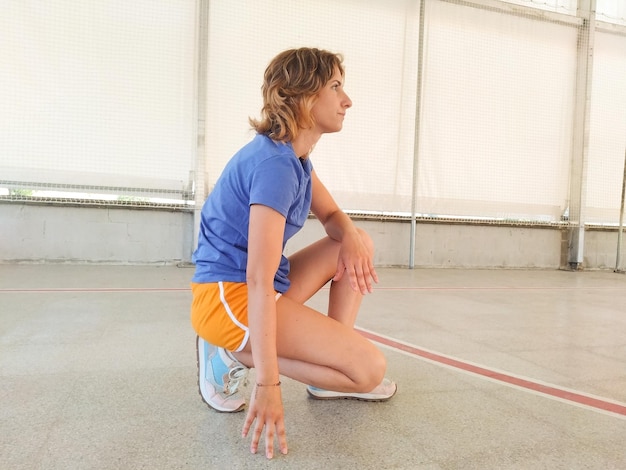 chica joven deportista sentada apoyada con una rodilla de un polideportivo