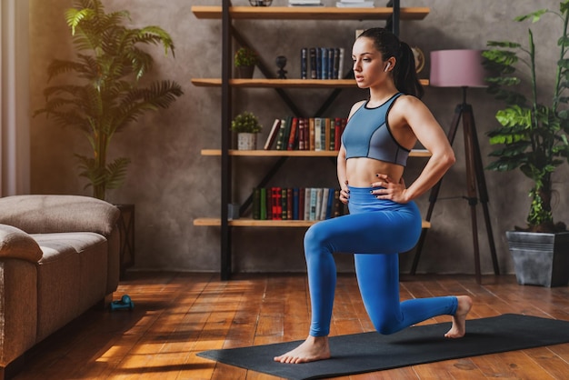 Chica joven deportiva haciendo estocadas trabajando para músculos de piernas y glúteos en casa