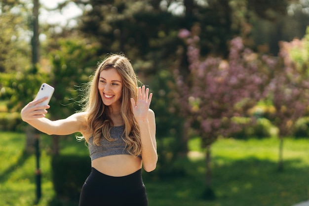 Chica joven deportiva con teléfono tomar foto selfie en el parque