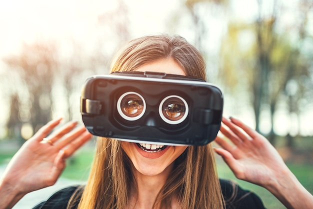 Chica joven disfruta de gafas de realidad virtual al aire libre