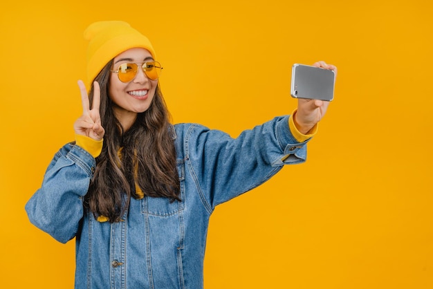 Chica joven divertida en sombrero amarillo posando aislado sobre fondo amarillo