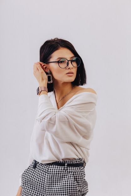 Foto chica joven elegante atractiva en ropa de negocios posando en la pared de luz en estudio. concepto de ropa elegante y sofisticación.