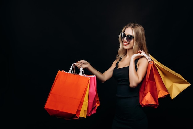Chica joven con elegante vestido negro está satisfecha con las compras