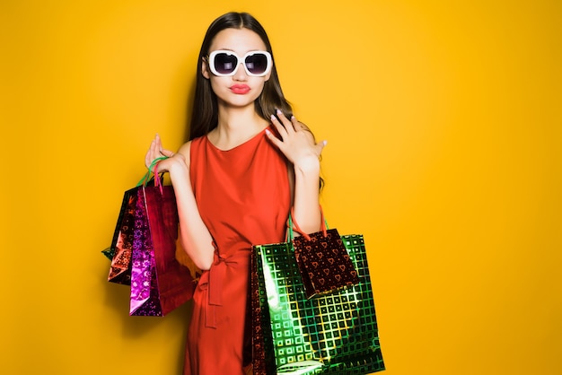 Chica joven elegante con un vestido rojo y gafas de sol fue de compras en un viernes negro