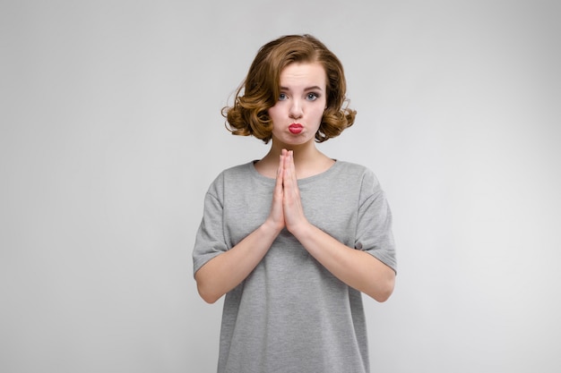 Chica joven encantadora en una camiseta gris en un gris