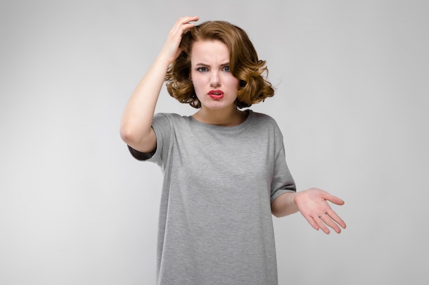 Chica joven encantadora en una camiseta gris en un gris