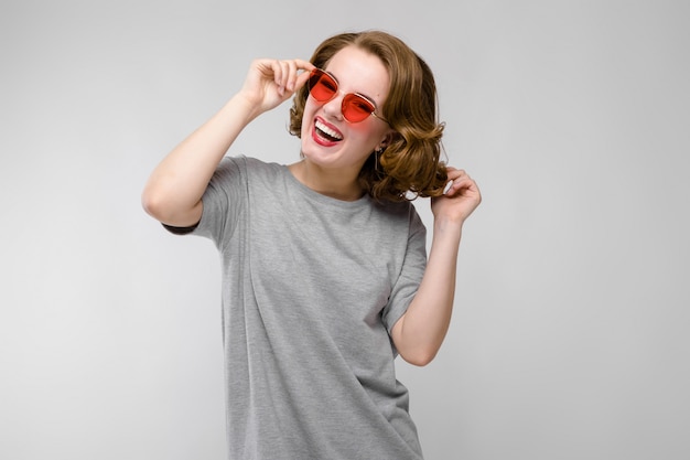 Chica joven encantadora en una camiseta gris en un gris