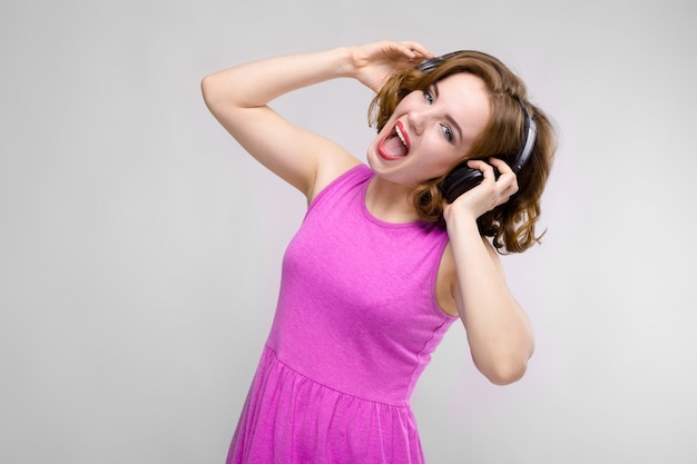 Chica joven encantadora en vestido rosa en gris