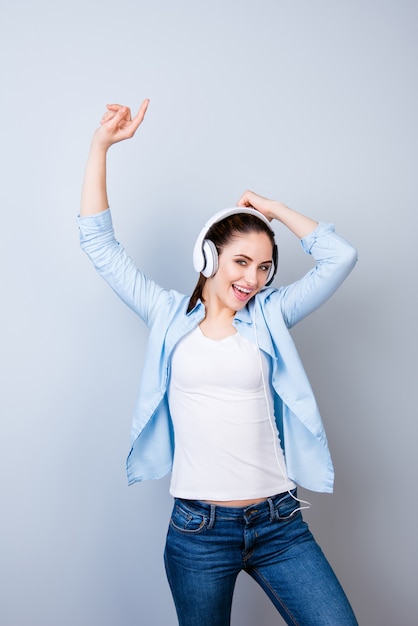 Chica joven enérgica escuchando música en auriculares y bailando