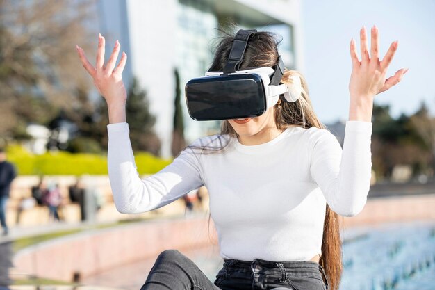 Chica joven con equipo de realidad virtual levantando las manos Foto de alta calidad