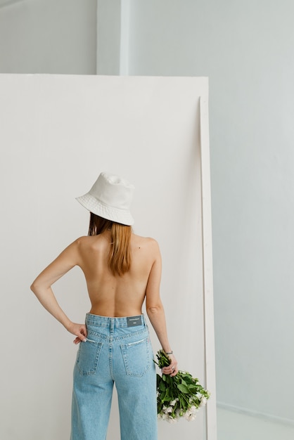 Chica joven con la espalda desnuda en jeans azules y un sombrero de Panamá