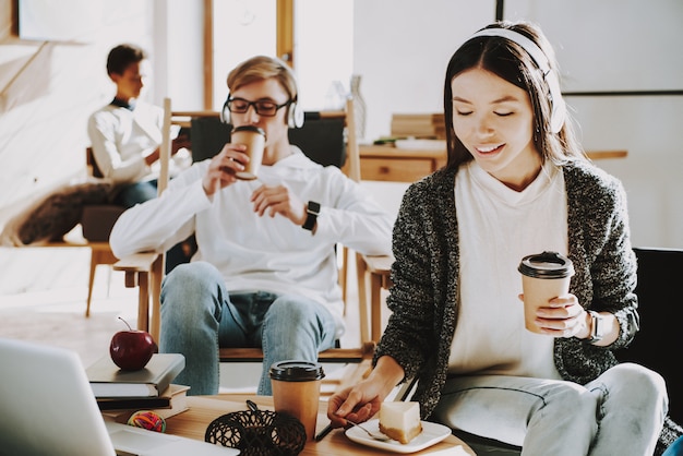 Chica joven está tomando café en los auriculares