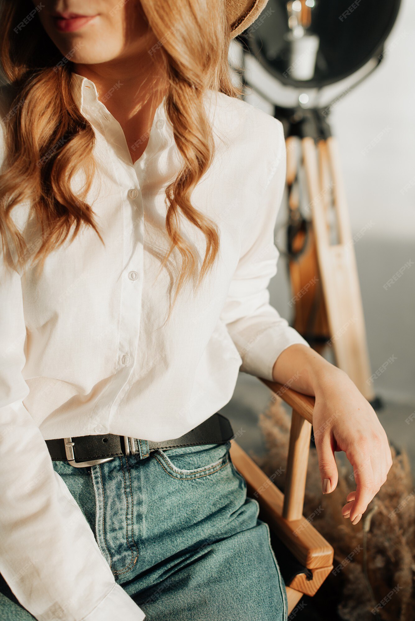 Chica joven con estilo en jeans y camisa blanca sienta en una de madera | Foto Premium