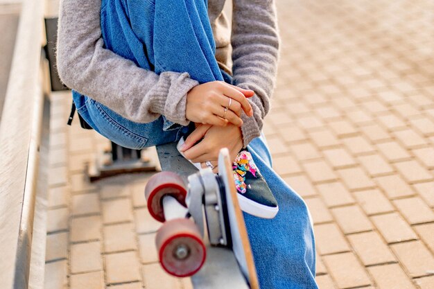 Chica joven con estilo urbano caminando con monopatín. Retrato al aire libre de modelo de mujer deportiva activa. Estilo de vida saludable. Deportes extremos. Look de moda, retrato hipster al aire libre. Close Up retrato de un prett