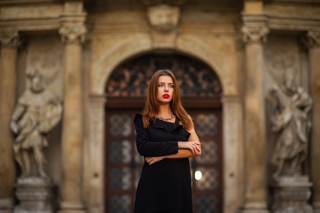 Chica joven con estilo en un vestido negro en la calle de la ciudad de BRNO en la mañana.