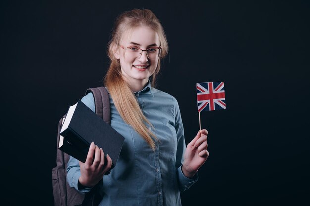 Chica joven estudiante de jengibre demostrando libros y bandera británica