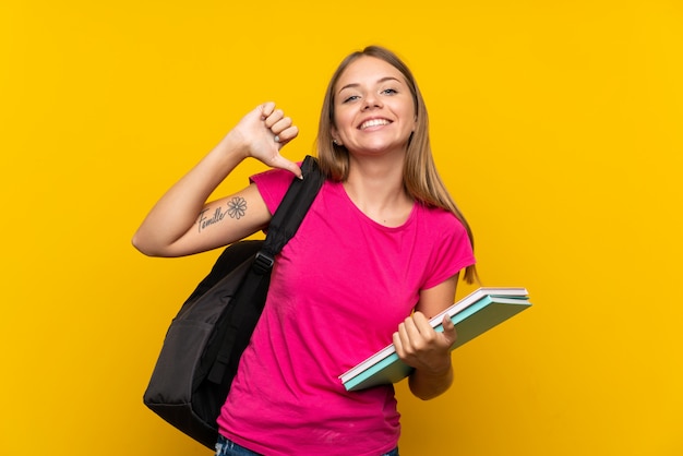 Chica joven estudiante sobre fondo amarillo aislado orgulloso y satisfecho de sí mismo