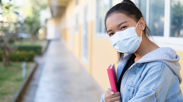 Chica joven estudiante usa máscara caminando en la escuela