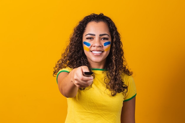 Chica joven fan brasileña con controlador en mano listo para ver el juego brasileño