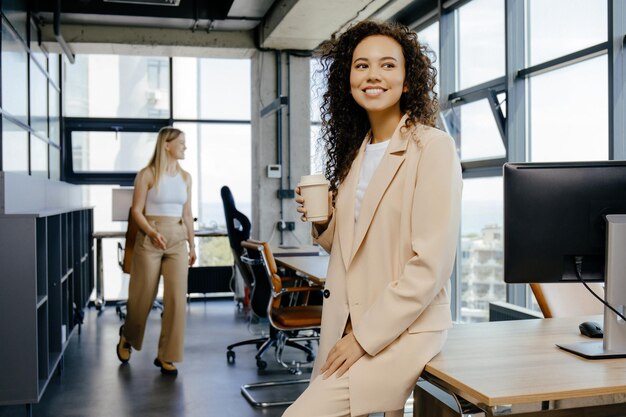 Chica joven feliz bebiendo café en el almuerzo en la oficina