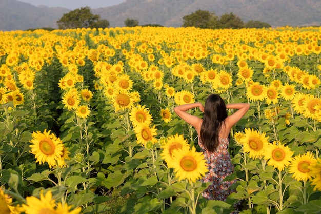 Chica joven feliz en el campo de flores en verano