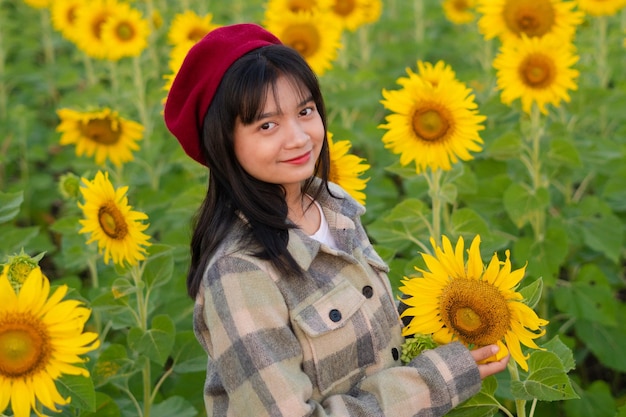 Chica joven feliz en el campo de girasol con cielo azul