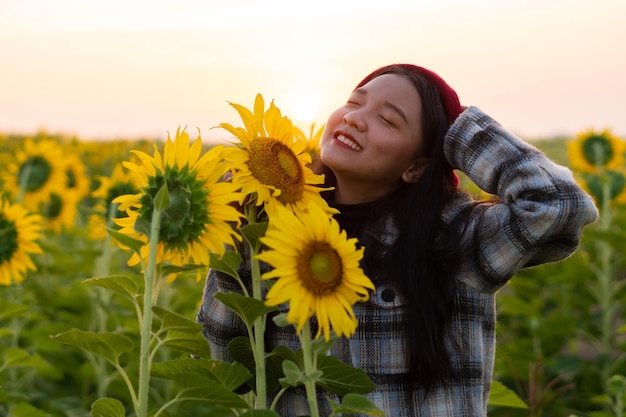 Chica joven feliz en el campo de girasol con cielo azul