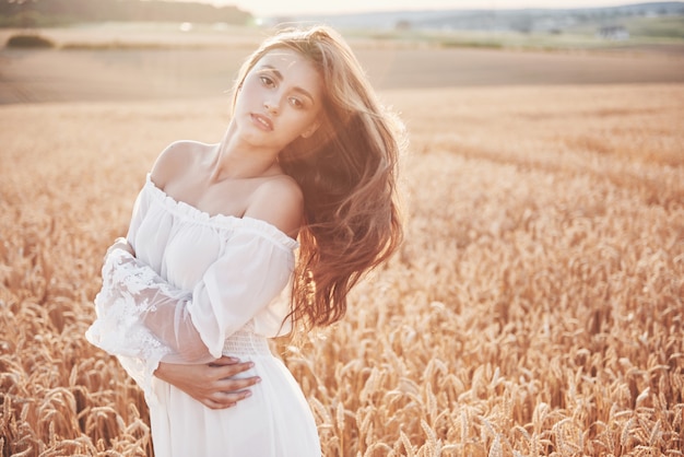 Chica joven feliz en un campo de trigo bajo luz del sol.