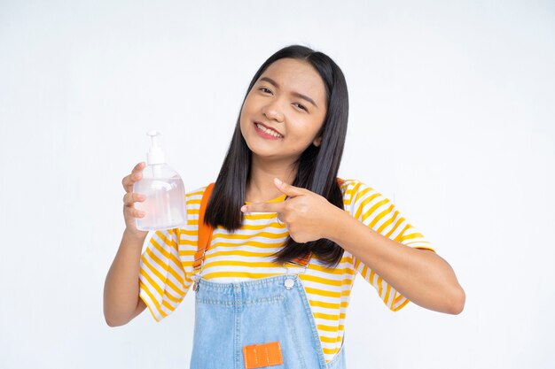 Chica joven feliz con gel de alcohol sobre fondo blanco.