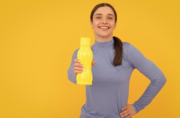 Chica joven feliz ofrece botella de deporte con hidratación de agua