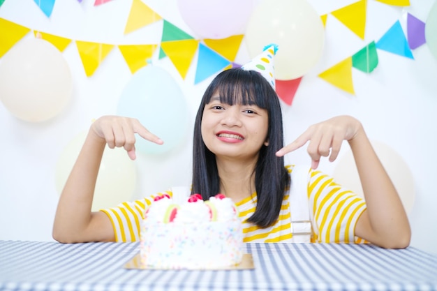 Chica joven feliz con pastel en la fiesta de cumpleaños sobre fondo blanco.